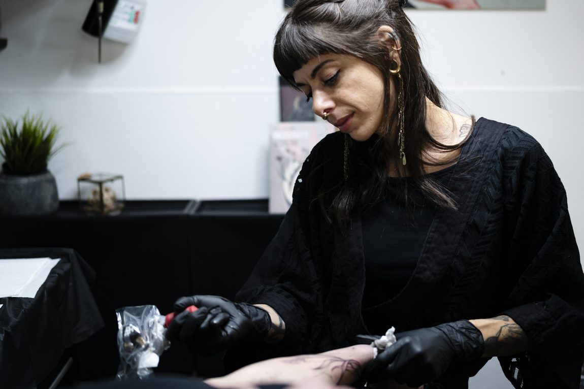 La tatuatrice al lavoro, la macchinetta in mano. Ora Berlin Tattoo, Berlino.