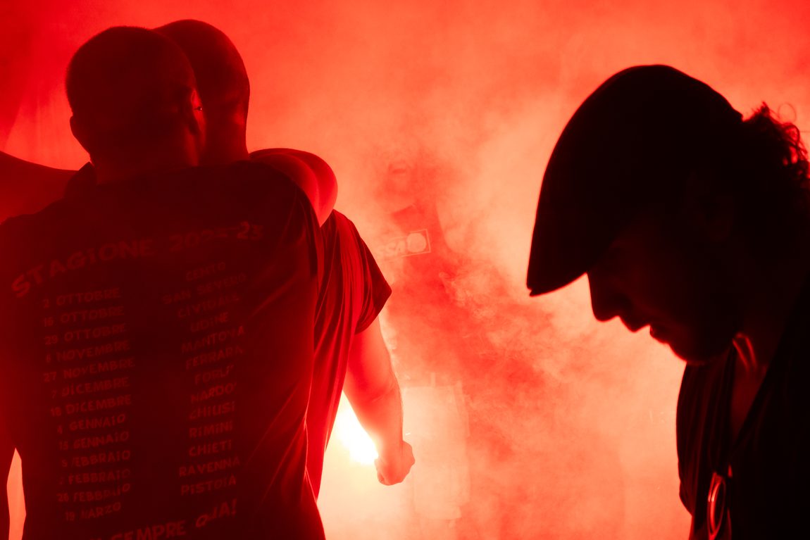 Due sagome dentro il fumo rosso. FAITH · Fossa dei Leoni, Bologna.